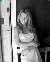 Black and white image of Britney on the porch again leaning against a post.